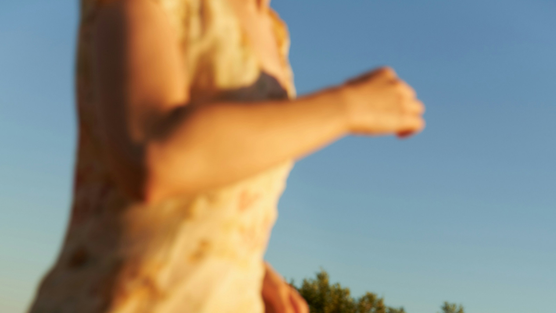 Woman in a sunlit dress against a blue sky