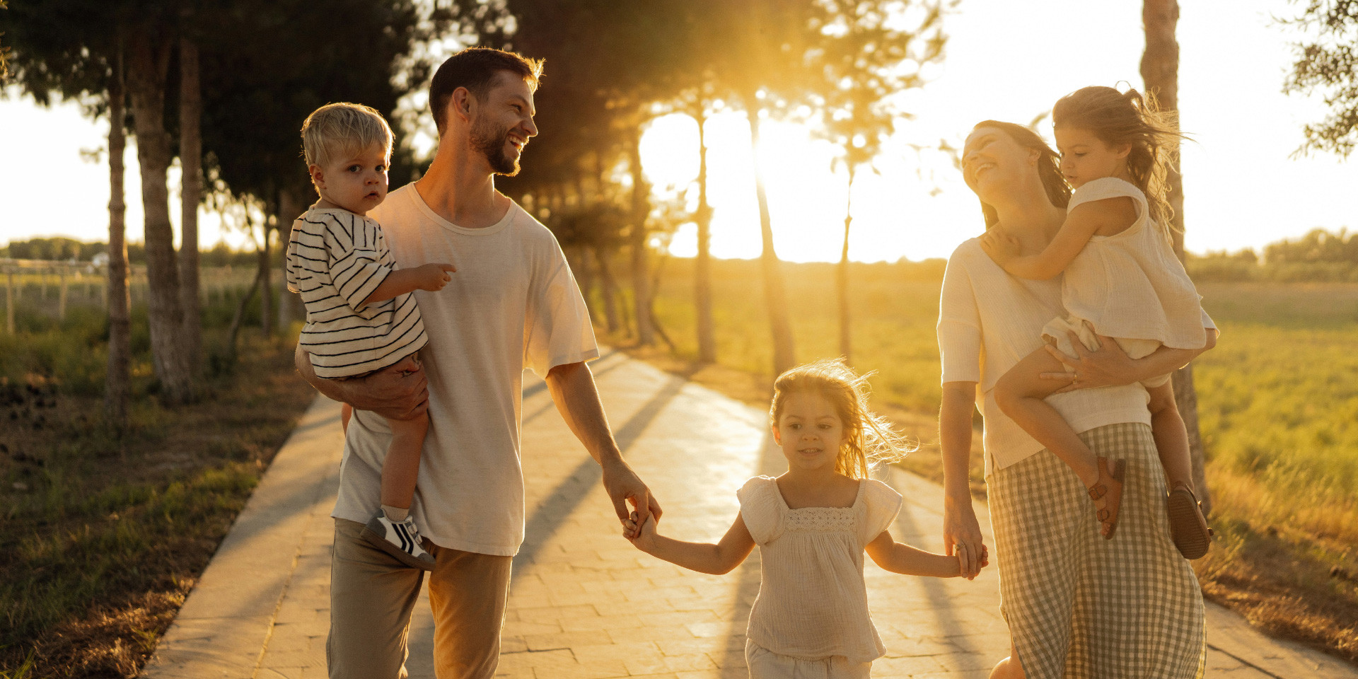 Family walking along a tree lined path at sunset